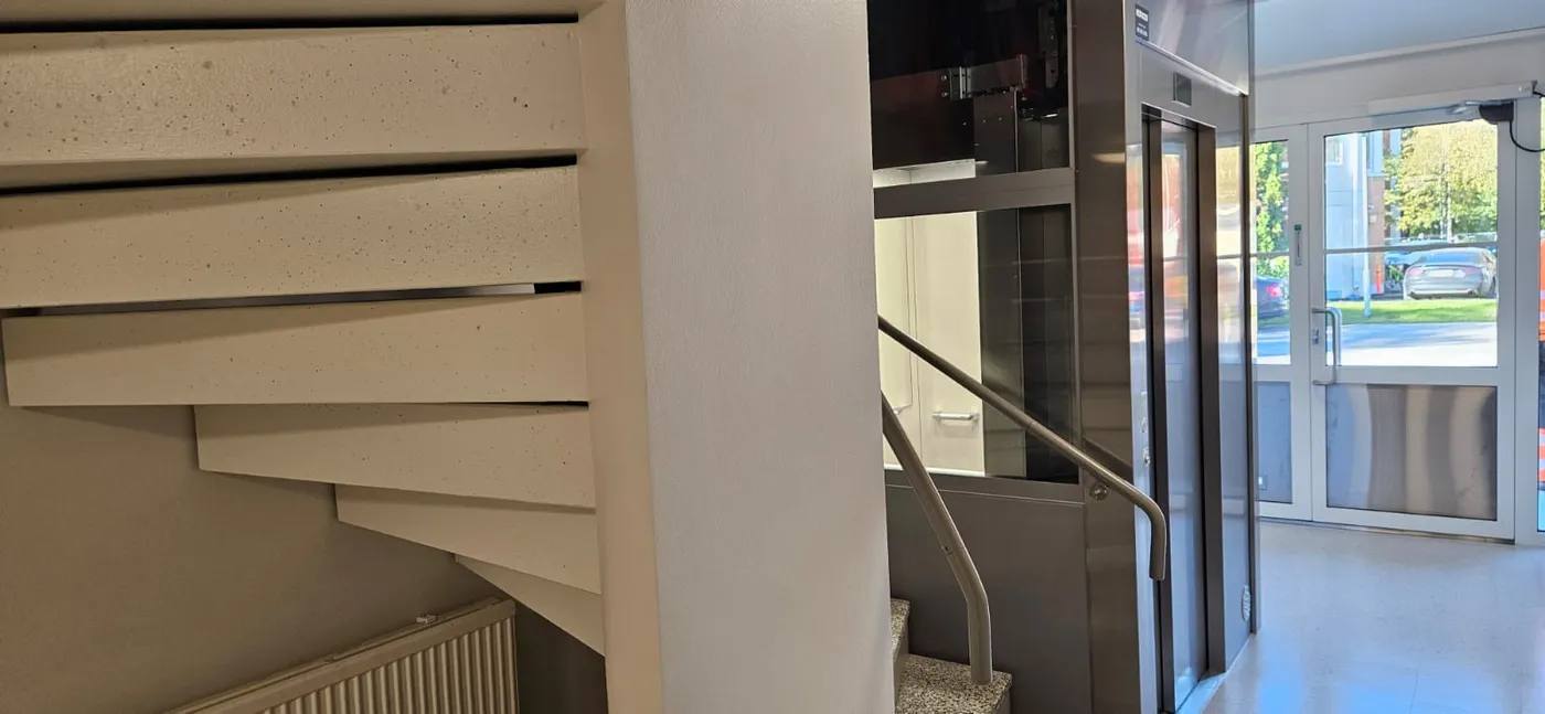 Asennettu mosaiikkibetoniporras ja jälkiasennushissi valmiissa porrashuoneessa