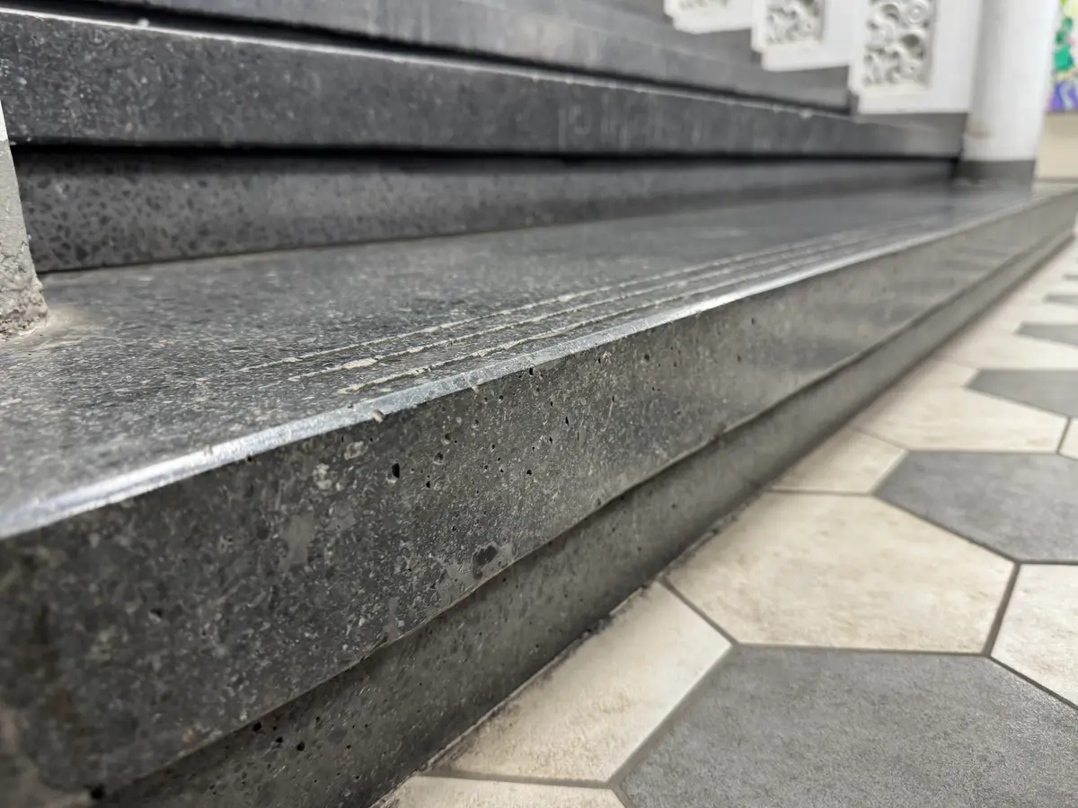 Uritettu mosaiikkibetoniaskelma — askelman etureunaan hiotut liukuesteurat tummassa mosaiikkibetonissa